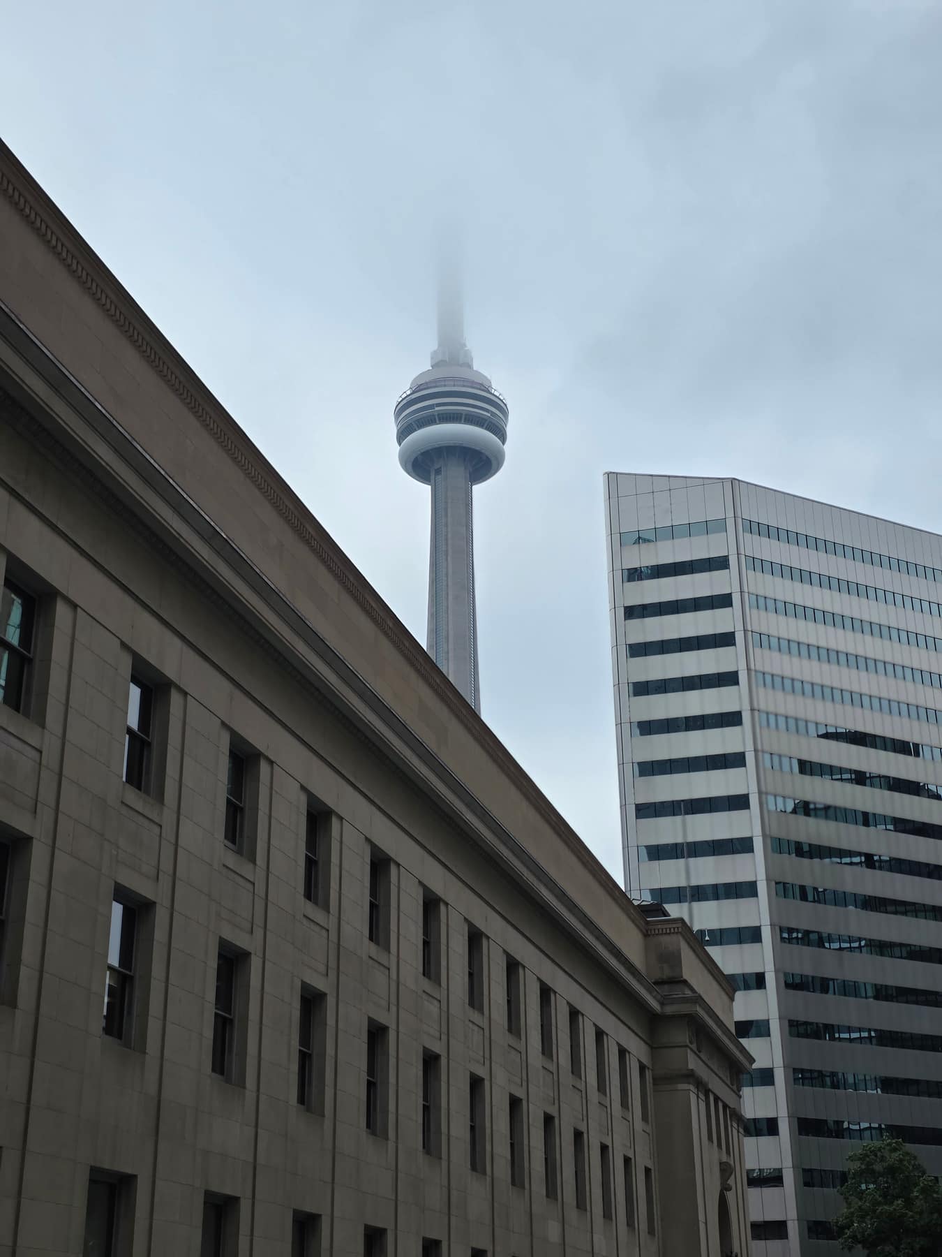 The CN Tower with its top swallowed by low cloud, seen over Union Station.
